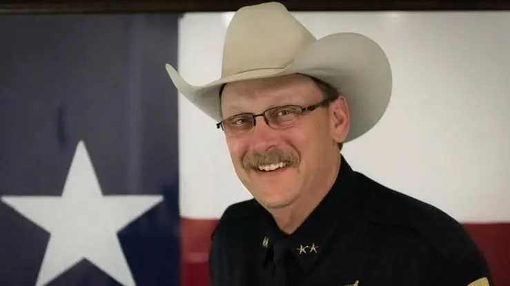 Sheriff Adam King of Johnson County, Texas, in uniform in front of the Texas state flag